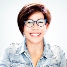 Headshot of a woman in a jacket, wearing glasses, smiling.