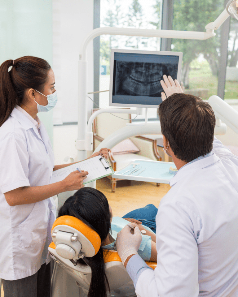 dental office with doctor, patient, and dental assistant viewing a computer screen