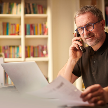 Man on the phone working at a desk reviewing paper work